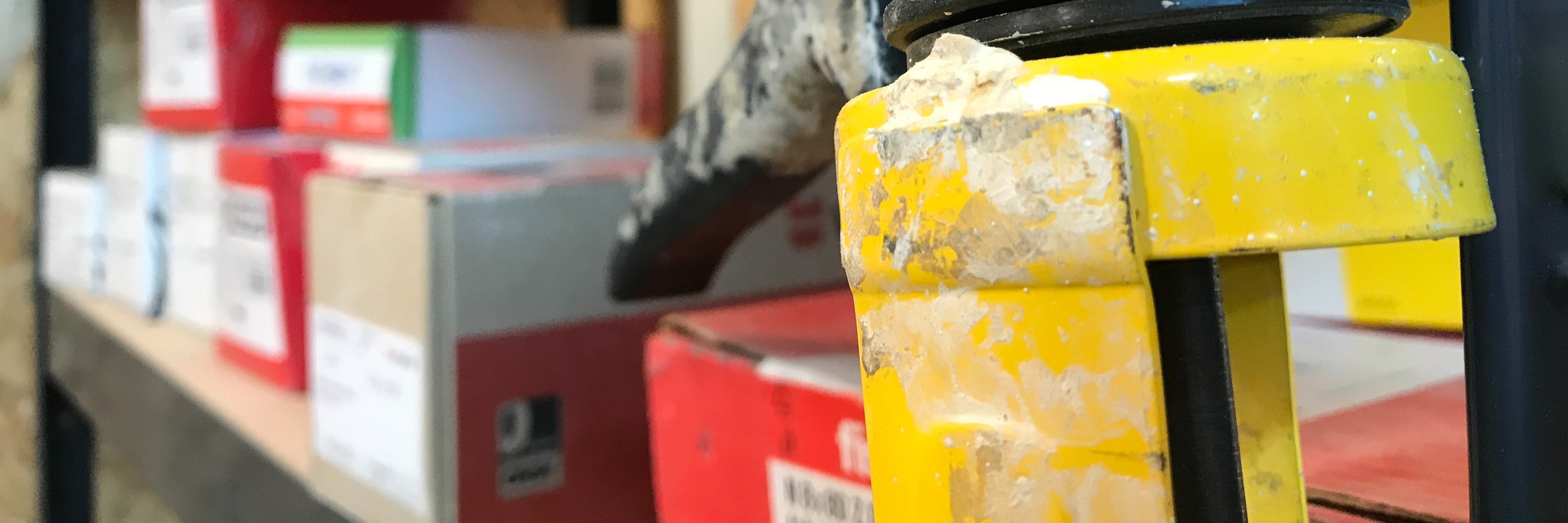 Detailansicht verschiedner Verpackungen von Materialien und im Vordergrund eine gelbe Silikonspritzmaschine.